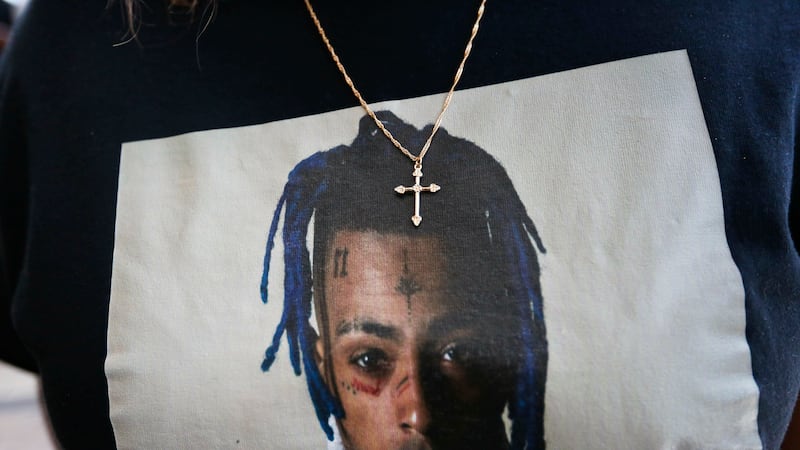 FILE - In this June 27, 2018, file photo a fan wears a cross around her neck dangling on a...